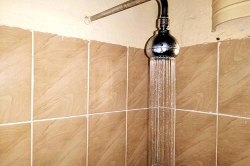 a shower head in a bathroom with tiles at Remarkable 3-Bed Cottage in Nyanga in Juliasdale