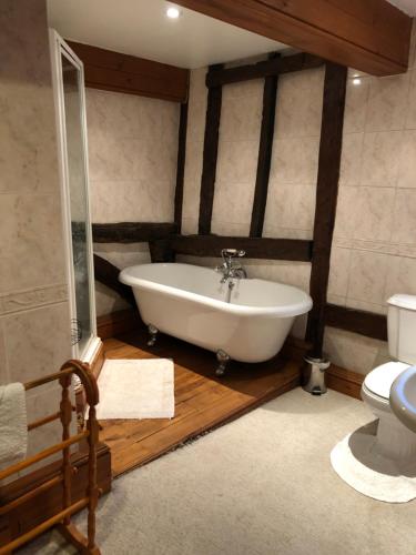 ein Bad mit einer Badewanne und einem WC in der Unterkunft The Walnuts Country House in West Row