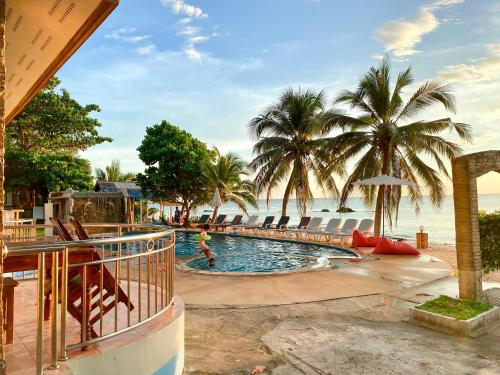 una piscina junto a una playa con palmeras en Lanta Paradise Beach Resort, en Ko Lanta