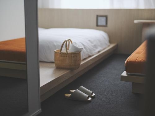 a hotel room with a bed and a pair of slippers at SOKI Kanazawa in Kanazawa