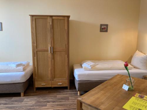 a room with two beds and a cabinet and a table at Landhotel Vosse-Schepers in Rhede