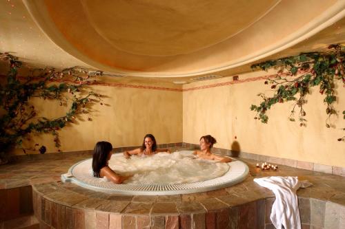 Tre donne in una vasca idromassaggio in una stanza di Hotel Menardi a Cortina dʼAmpezzo