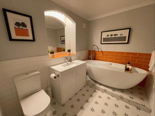 a bathroom with a tub and a toilet and a sink at East Walls Apartment in Chichester