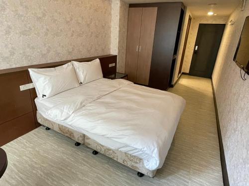 a bedroom with a bed with white sheets and pillows at 苓旅-站前 Lin Inn TMS in Taipei