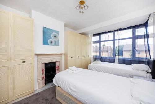 a bedroom with two beds and a fireplace at Head-on-Beds -Dagenham Larger Groups with Free Parking in Dagenham