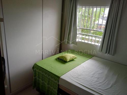 ein Bett mit einer grünen Decke und einem Fenster in der Unterkunft Apto Aconchegante a 20 mts do Mar e Pertinho do Centro in Matinhos