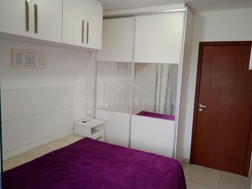 1 dormitorio con cama morada y armarios blancos en Apto Aconchegante a 20 mts do Mar e Pertinho do Centro en Matinhos