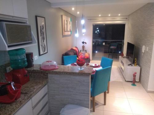 a kitchen with a table and blue chairs in a room at Apto Aconchegante a 30 mts do Mar e Pertinho do Centro in Matinhos