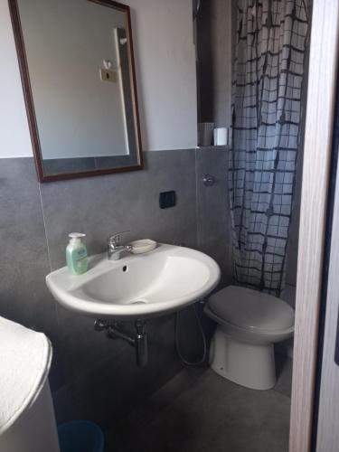 Un baño con lavabo, inodoro y espejo. en Terrazza delle mura, en Cefalú
