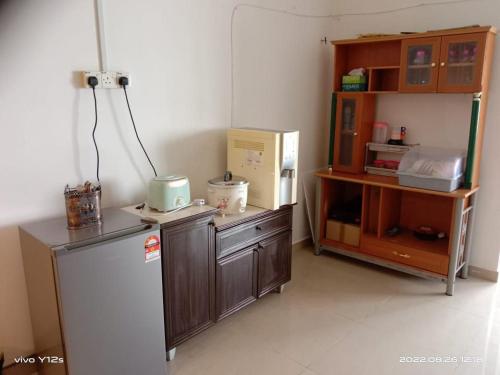 Il comprend une cuisine équipée d'un réfrigérateur blanc et d'une étagère. dans l'établissement Rizqy Homestay di Jitra, à Jitra