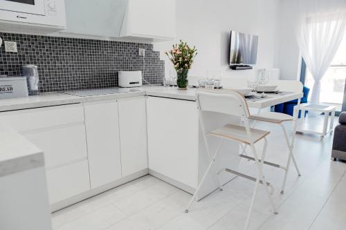 a kitchen with white cabinets and a table and chairs at GARDENIA SUPERIOR apartament 33 in Dziwnów
