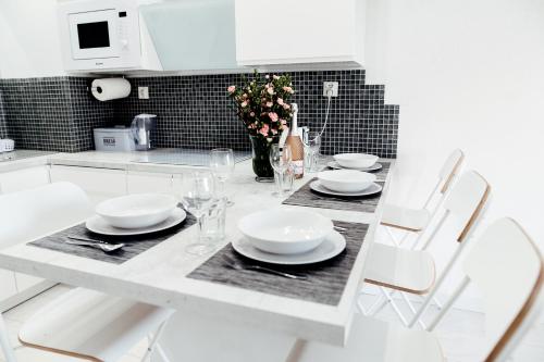 a white kitchen with a table with plates and a vase of flowers at GARDENIA SUPERIOR apartament 33 in Dziwnów