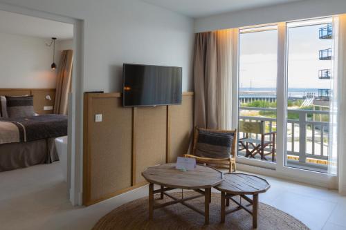 a hotel room with a bed and a tv and a table at Noordzee, Hotel & Spa in Cadzand-Bad