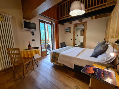 a bedroom with a bed and a table and a television at Hotel Aigle in Courmayeur