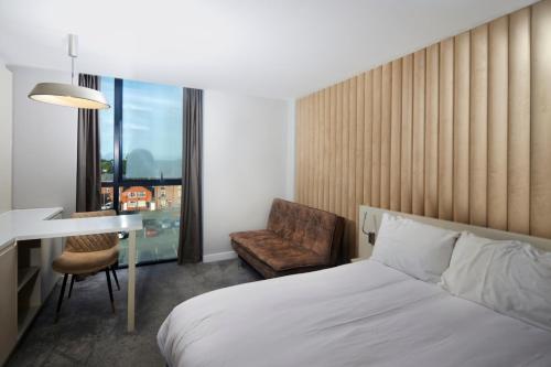 LUSSO Macclesfield Serviced Apartments في ماكليسفيلد: غرفة في الفندق بسرير وكرسي ومكتب