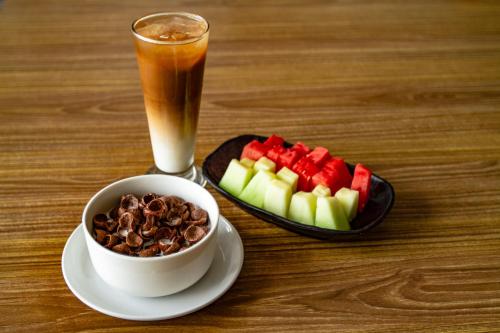 a cup of coffee and a bowl of nuts and a plate of fruit at Hotel Summerville in Majalengka