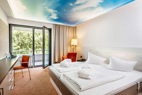 ein Hotelzimmer mit einem Bett, einem Schreibtisch und Stühlen in der Unterkunft Thermenhotel Gesundheits-Bad Buchau in Bad Buchau