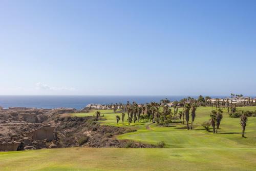 a golf course with palm trees and the ocean at Barceló Tenerife in San Miguel de Abona