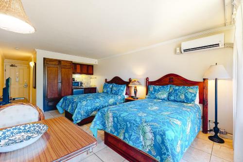 a bedroom with two beds and a table at Islander on the Beach 370 in Kapaa