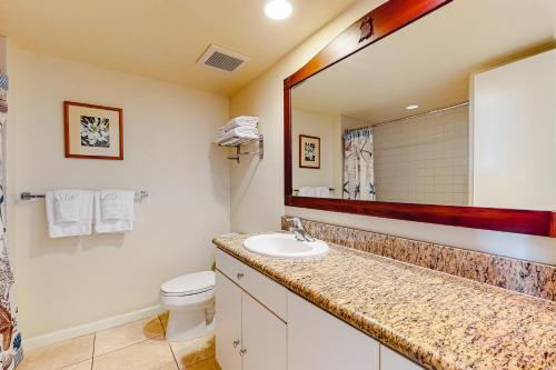 a bathroom with a sink and a toilet and a mirror at Islander on the Beach 370 in Kapaa