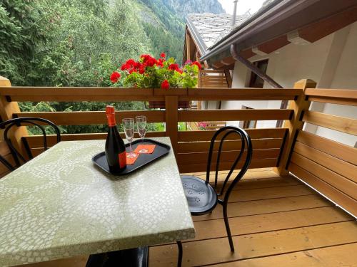 a table with a bottle of wine and glasses on a balcony at Hotel Aigle in Courmayeur
