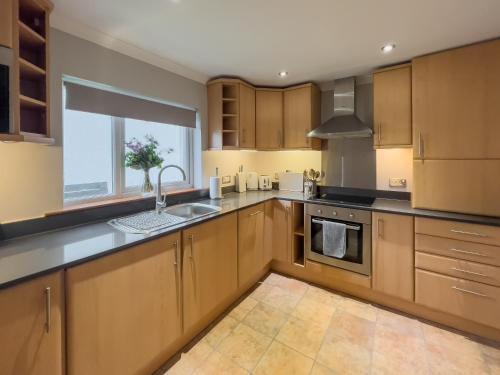 a kitchen with wooden cabinets and a large window at Luxury Pitlochry Retreat- Cairngorms Ntl Park Gateway in Pitlochry