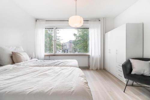 ein Schlafzimmer mit einem Bett, einem Stuhl und einem Fenster in der Unterkunft Cosy flat with good transport connections in Vantaa