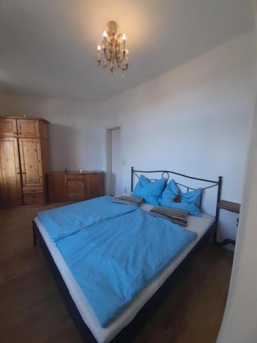 a bedroom with a blue bed with a chandelier at Appartements Donaublick in Linz