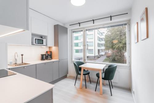 eine Küche mit einem Tisch und Stühlen sowie einem Fenster in der Unterkunft Cosy flat with good transport connections in Vantaa