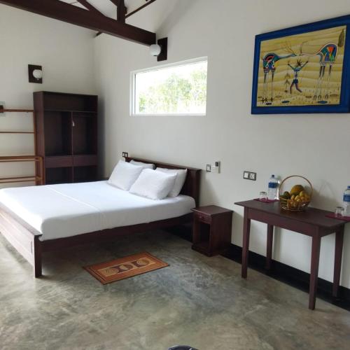 a bedroom with a bed and a table and a window at Edelweiss Residence in Hikkaduwa