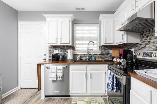 a kitchen with white cabinets and a stainless steel refrigerator at Unique Cozy Home 6 Min 2 Uptown Fire Pit & Yard in Charlotte