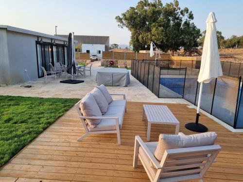 eine Terrasse mit 2 Stühlen, einem Tisch und einem Sonnenschirm in der Unterkunft זריחה למרגלות הגלבוע in Nurit