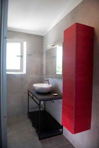 a bathroom with a sink and a red cabinet at Lough appartamento in Colà di Lazise