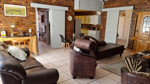 a living room with two couches and a kitchen at MFT GUEST HOUSE in Boksburg