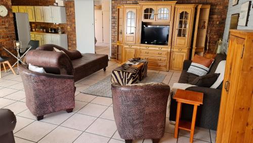 a living room with couches and chairs and a television at MFT GUEST HOUSE in Boksburg