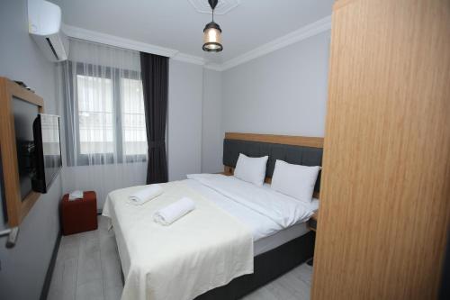 um quarto com uma cama com lençóis brancos e uma televisão em AKTAŞ SUITE em Trebizonda