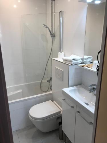 a white bathroom with a toilet and a shower at Hôtel Flor Rivoli in Paris