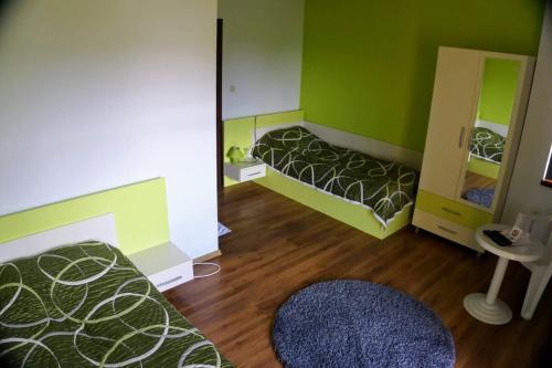 a green room with two beds and a mirror at Guest House Arima in Sushina
