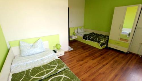 a green room with a bed and a mirror at Guest House Arima in Sushina