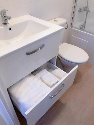 une salle de bain blanche avec un lavabo et des toilettes dans l'établissement petite maison avec jardin dans banlieue de Paris, à Cormeilles-en-Parisis