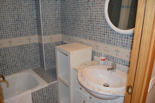 uma casa de banho em azulejos azuis com um lavatório e uma banheira em Apartamento Pleta de Soldeu em Soldeu