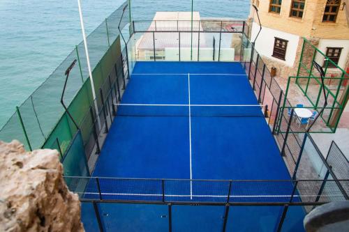 an overhead view of two tennis courts next to the water at Radisson Blu Hotel, Kuwait in Kuwait