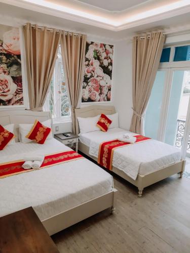 twee bedden in een kamer met ramen en gordijnen bij thiên phú hotel in Ho Chi Minh-stad