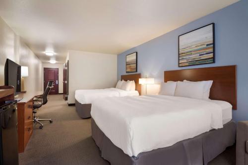 a hotel room with two beds and a desk at Best Western Coffeyville Central Business District Inn and Suites in Coffeyville
