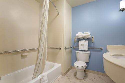 a bathroom with a toilet and a tub and a sink at Best Western Coffeyville Central Business District Inn and Suites in Coffeyville