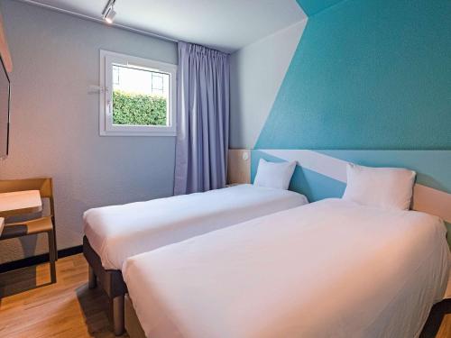 2 camas en una habitación de hotel con ventana en ibis Budget La Teste Bassin d'Arcachon, en La Teste-de-Buch