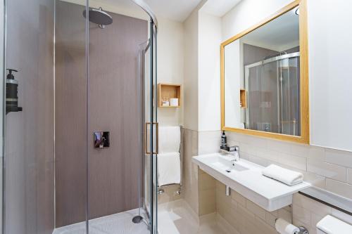 a bathroom with a shower and a sink and a mirror at Aberystwyth Park Lodge Hotel in Aberystwyth