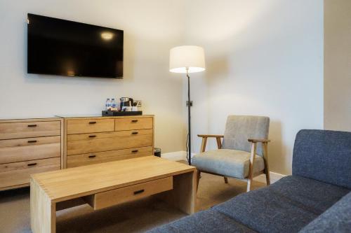 a living room with a bed and a dresser and a chair at Aberystwyth Park Lodge Hotel in Aberystwyth
