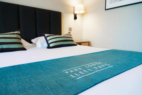 a bedroom with a bed with a blue blanket on it at Aberystwyth Park Lodge Hotel in Aberystwyth