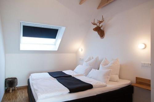 Schlafzimmer mit einem Bett mit weißer Bettwäsche und einem Fenster in der Unterkunft Ferienapartment 2 Sielzeit in Neuharlingersiel